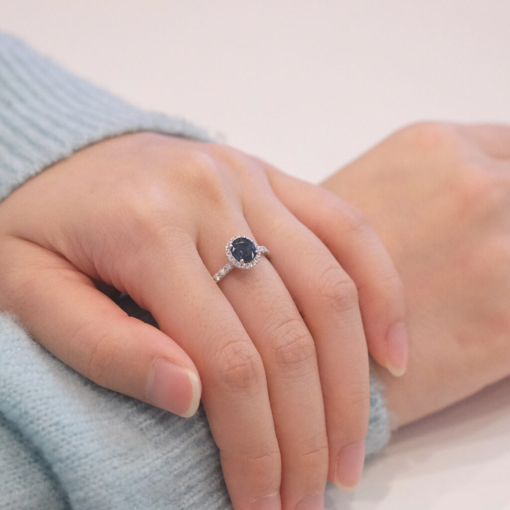 Blue sapphire gemstone with halo diamond engagement ring on hand