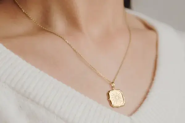 gold pendant with hand grabbing sun engraving