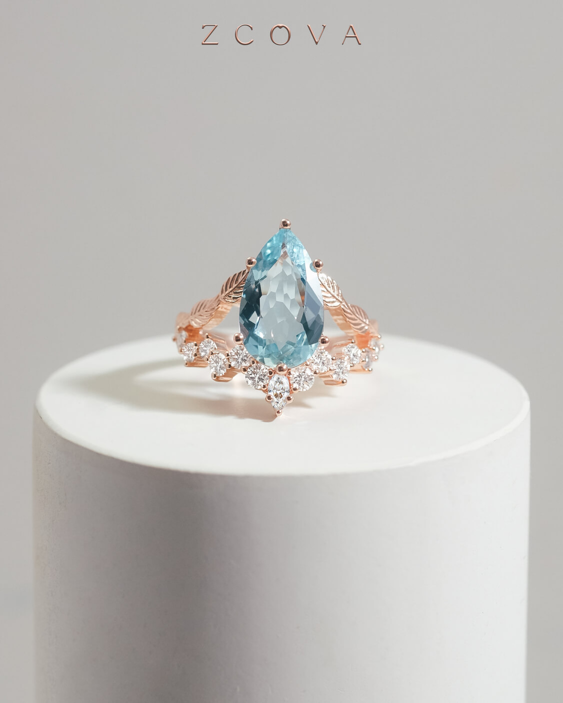 Rose gold ring with light blue pear shaped aquamarine stone with leaf and diamond split shank